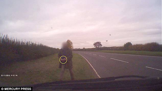 In a dashcam footage filmed on the side of the road, a man can be seen walking towards a vehicle